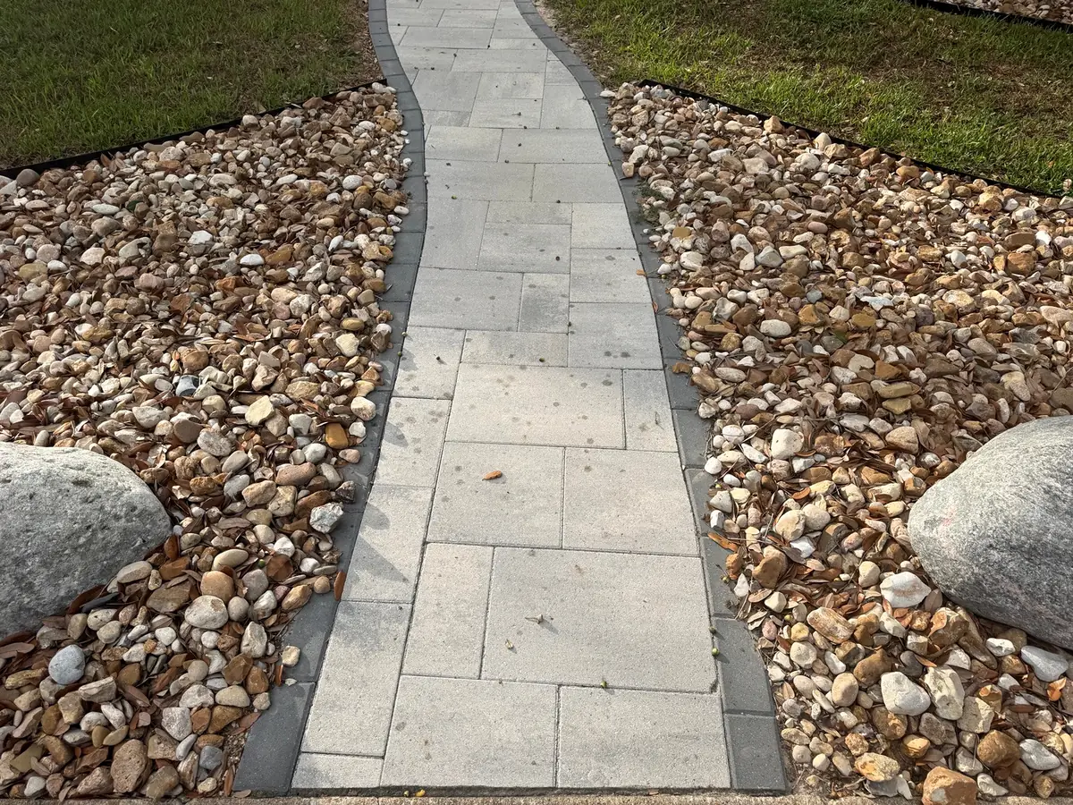 Paver walkway running between river rock beds
